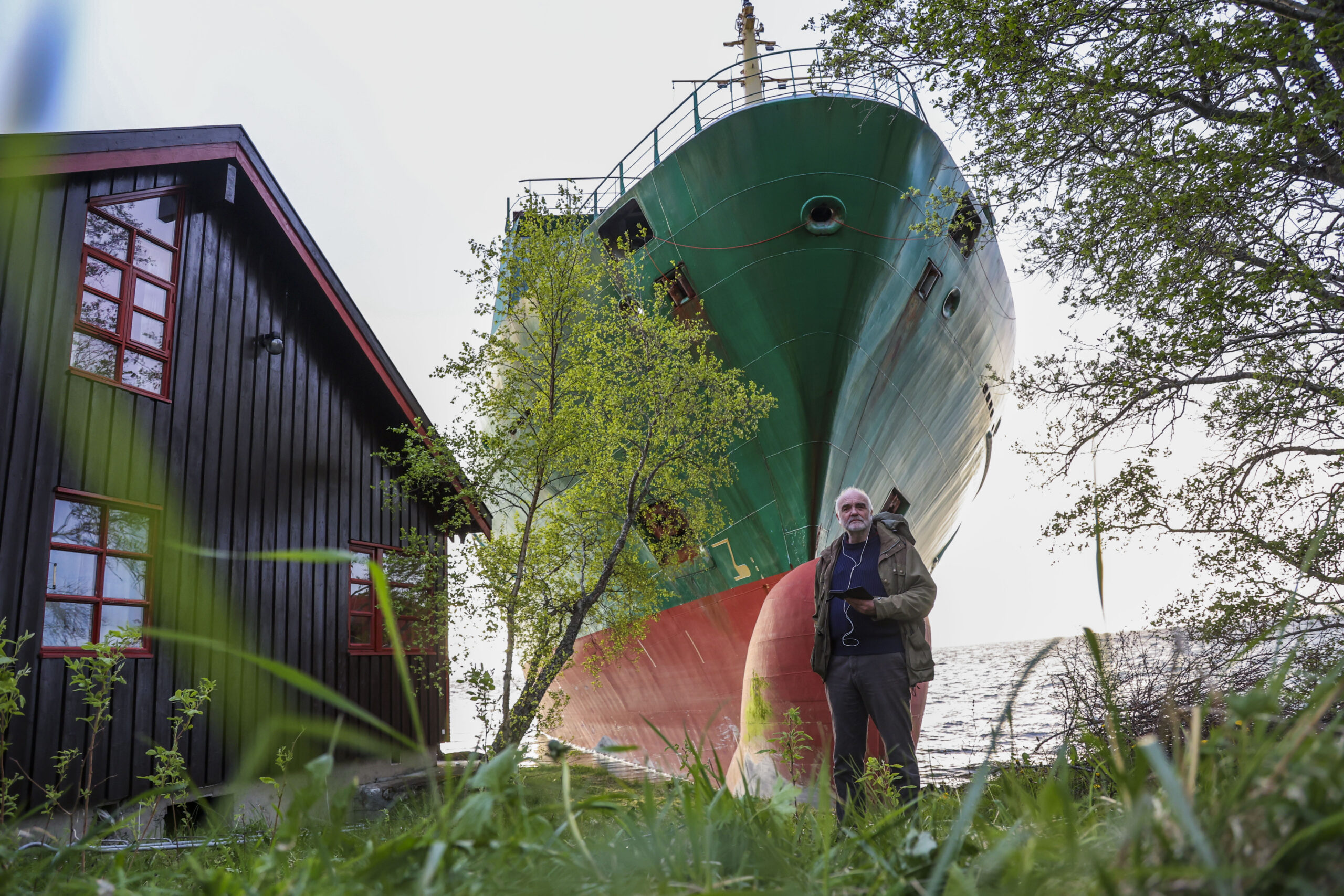 Man Wakes Up and Sees 440-Foot Ship in His Garden. LOL! (Photo: Johan Helberg stands next to his house, with the container ship NCL Salten in the background, after the 135-meter-long ship ran aground in the Trondheimsfjord, outside Byneset, in Trondheim, Norway, Thursday May 22, 2025. (Jan Langhaug/NTB Scanpix via AP)